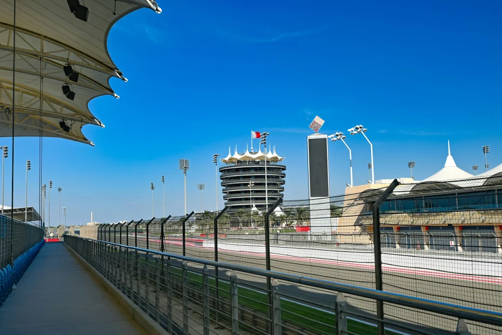 Vue sur les stands et la ligne droite du circuit de Formule 1 de Bahreïn, à Sakhir, sous un ciel bleu.